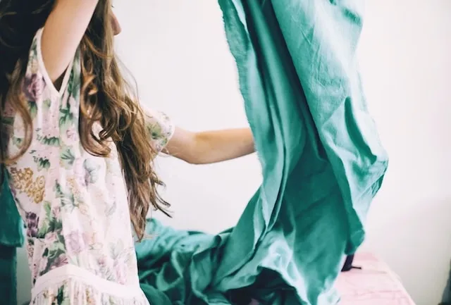 Woman lifting up a green tablecloth with wrinkles for How To Get Wrinkles Out Of Tablecloths